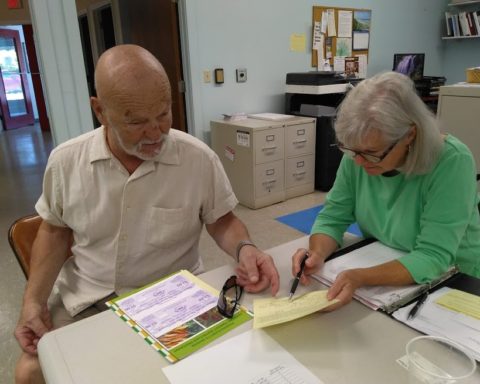 Franz Burnet-Gocht receives his farmers market coupons from Marion Quinn-Jowett; photo by Sheila Velazquez.