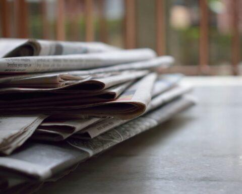 Close -up photo of a stack of newspapers on a wooden table.