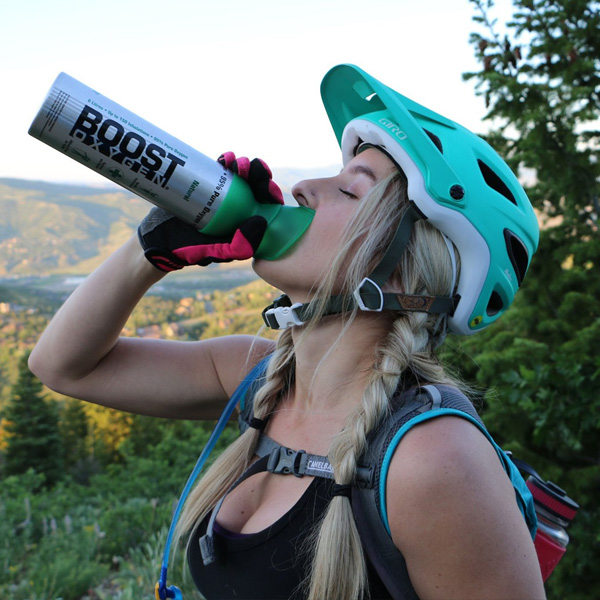 Photo of a young female mountain biker inhaling from a canister of Boost, portable oxygen.