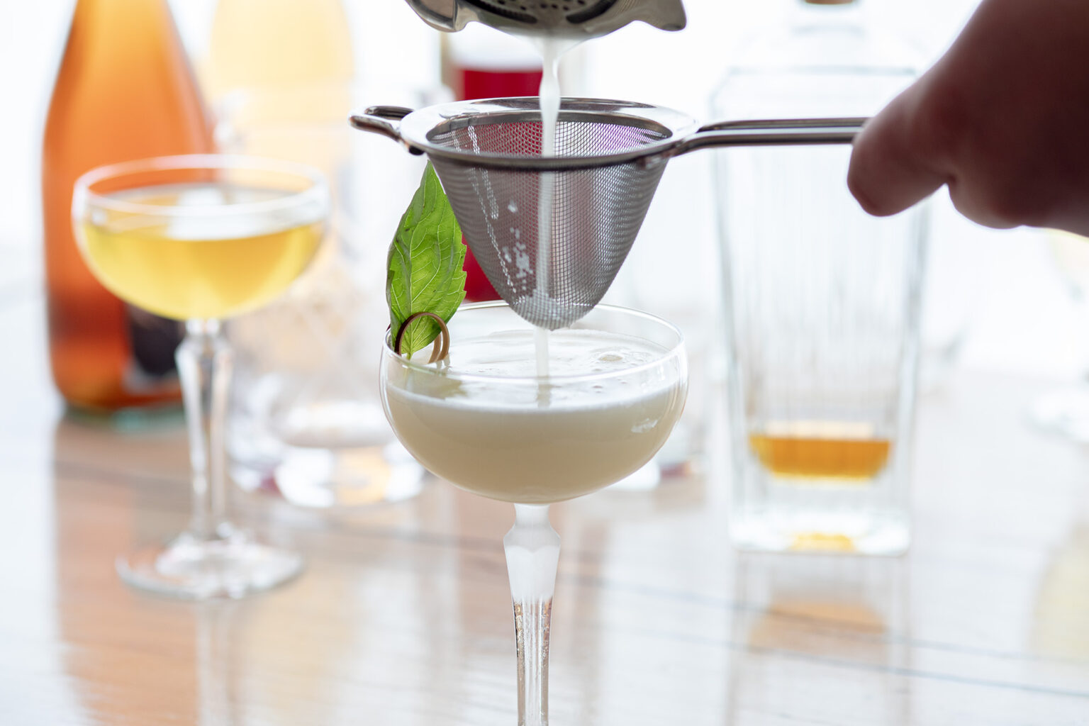 A strainer balances above a delicious cocktail.