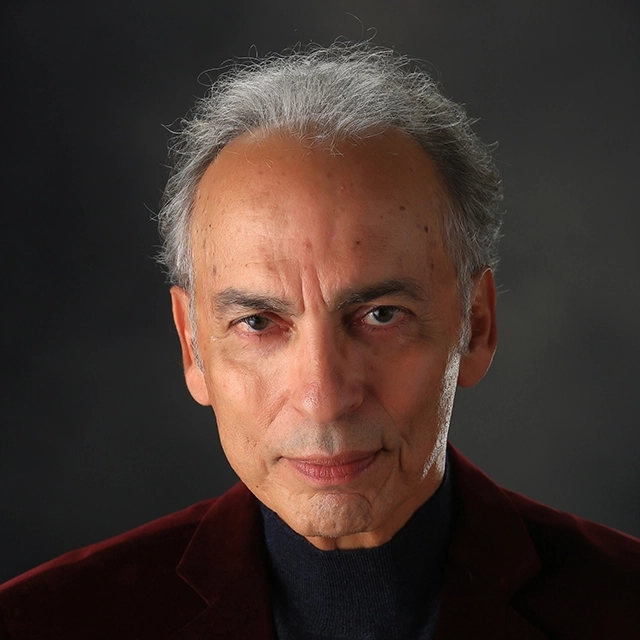 Headshot of a man, Tony Simotes, director of the staged reading "The Refuseniks" at The Adams Theater in August. Tony has a serious expression, with short, graying hair and is wearing a dark jacket against a dark background.